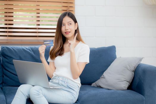 Young asian woman sitting thinking idea using credit card with laptop computer on couch, girl shopping online for buy and payment with notebook on sofa, finance and debit, lifestyle concept.