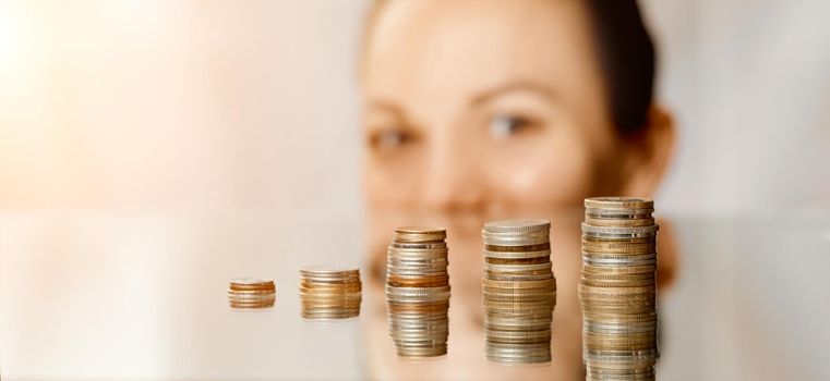 The girl looks out from the edge of the table and looks at the stacks of coins ladder . High quality photo