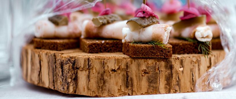 Canape of lard, bread, cucumber on a piece of wood under the film . High quality photo