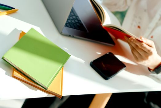 Woman checks notes in notepad working behind laptop at her desk at home for removal . High quality photo