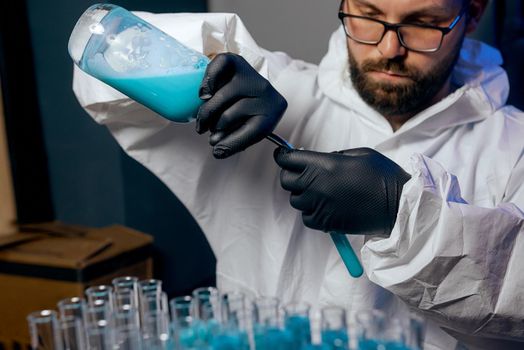 A man Scientist in a protective suit with flasks in his hands with a blue vaccine