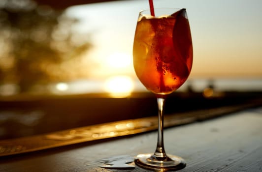 Cocktail glass with a tube on the background of the sea and sunset. High quality photo