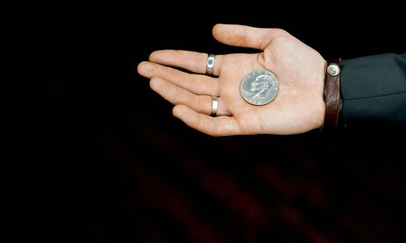 one coin in a man's palm on a black background local light. High quality photo