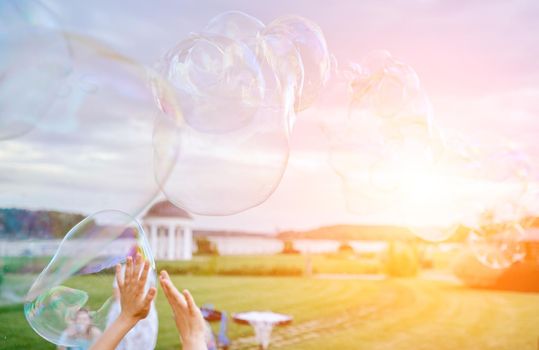 hands stretch to very large soap bubbles against the backdrop of nature . High quality photo