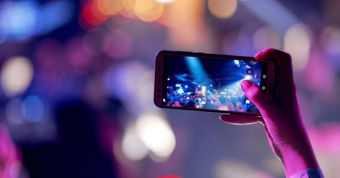 Hands silhouette recording video of live music concert with smartphone. High quality photo