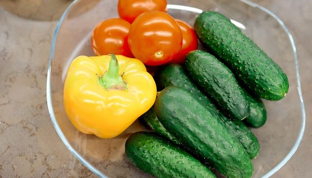 red tomato, green belly cucumber, yellow pepper, in a glass vase. High quality photo