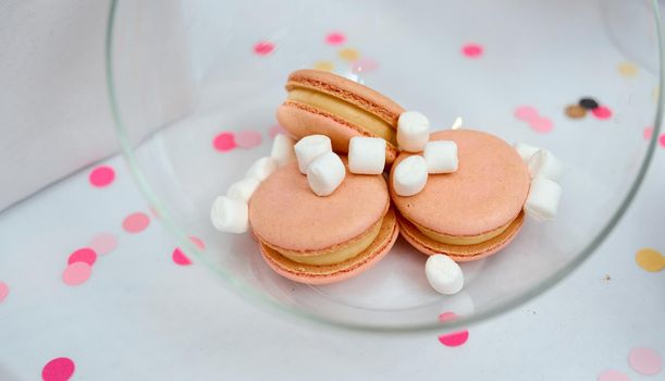 Colorful peach Macaroons with white marshmallows In A Glass Vase On White Table. High quality photo