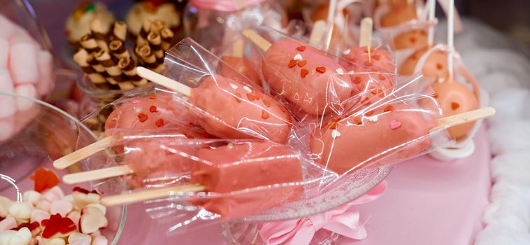 Lots of pink cakes in transparent glossy packaging on a plate. High quality photo