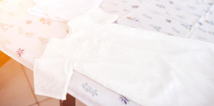 Woman dress clothes for newborn after christening on diaper . High quality photo