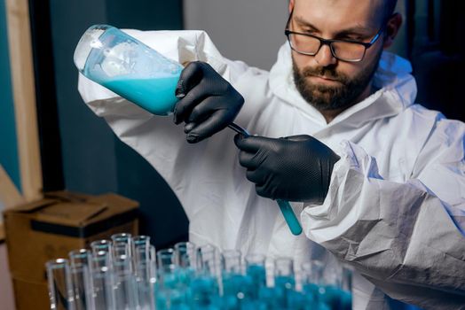  A man Scientist in a protective suit with flasks in his hands with a blue vaccine