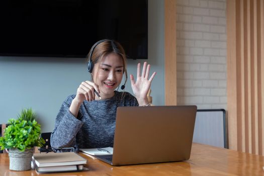 Shot smiling asian woman freelancer wearing headset, communicating with client via video computer call. Millennial pleasant professional female tutor giving online language class.