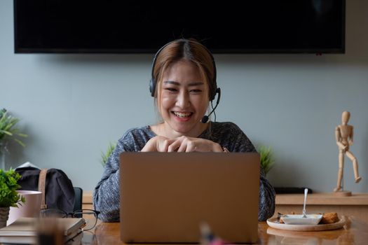 Shot smiling asian woman freelancer wearing headset, communicating with client via video computer call. Millennial pleasant professional female tutor giving online language class.