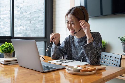 Shot smiling asian woman freelancer wearing headset, communicating with client via video computer call. Millennial pleasant professional female tutor giving online language class.