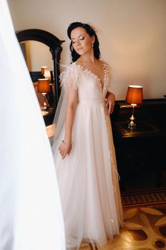 Portrait of the Bride in a wedding dress in the interior of the house near the mirror.