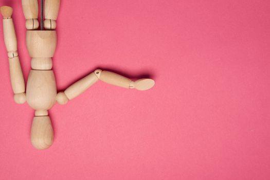 wooden mannequin on pink background posing close-up. High quality photo