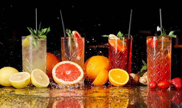 A few colorful fruit cocktails on a black background in water with splashes . High quality photo