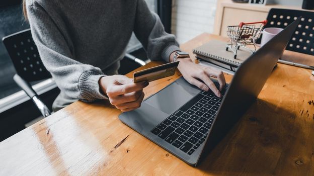 Close up young asian woman holding credit card and using tablet computer. Businesswoman working at home. Online shopping, e-commerce, internet banking, spending money, working from home concept.