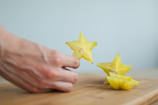 Female hands are holding slice of exotic ripe starfruit or averrhoa carambola. Healthy food, fresh organic star apple fruit.