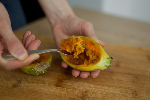 Female eats fresh organic ripe cactus pear or opuntia with a spoon. Exotic fruits, healthy eating concept.