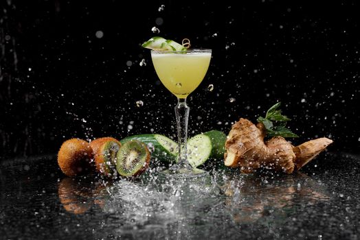 refreshing cocktail in splashes of water on a black background of cucumber kiwi and ginger. High quality photo