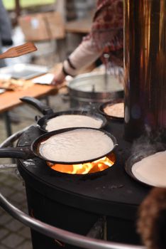 street cooking of pancakes on a large circular grill