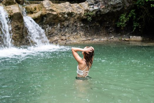 Tropical nature and vacation. Woman swimming in the mountain river with a waterfall