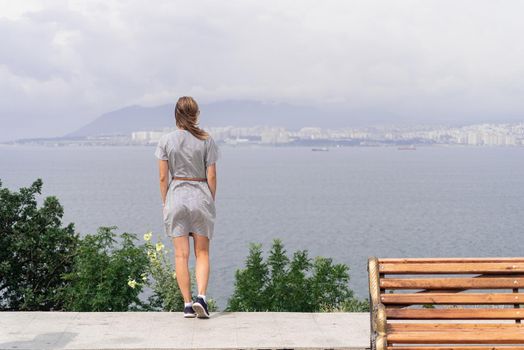 Back view of young woman in summer dress looking at the cityscape. Freedom concept. Travel concept