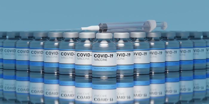 MANY CORONAVIRUS VACCINES LINED UP WITH A SYRINGE ON A GLASS TABLE WITH REFLECTIONS AND BLUE BACKGROUND