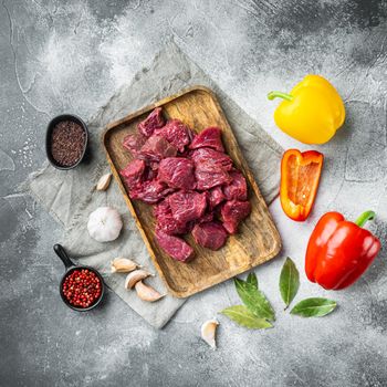 Irish raw Beef Stew Recipe ingredients set with sweet bell pepper, on gray stone background, top view flat lay, square format