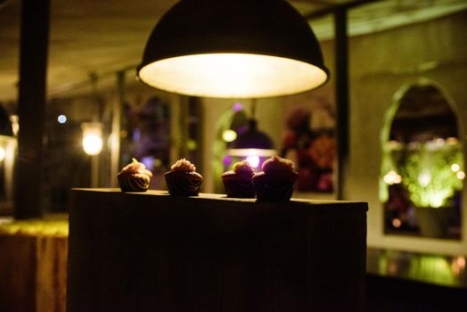 Backlighted cupcakes prestend on a wooden block in  a warm design interieur on a party