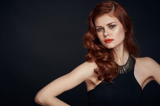 attractive red-haired woman in a black dress hairstyle dark background. High quality photo