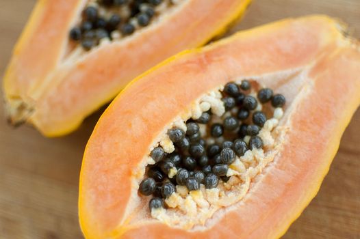 Fresh organic ripe papaya fruit cut in half on a wooden board. Exotic fruits, healthy eating concept.