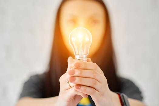 a woman holds an electric lamp that shines with warm light. The concept of a new idea. High quality photo