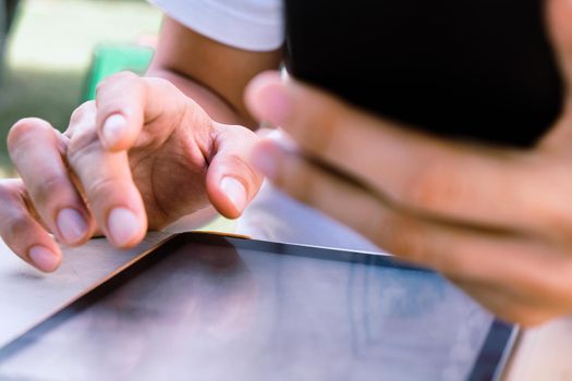 Close up image of a man using mobile smart phone and digital tablet