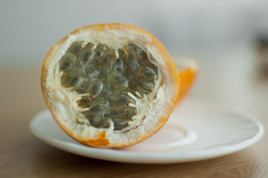 Fresh organic ripe granadilla or yellow passion fruit cut in half on a wooden board. Exotic fruits, healthy eating concept.