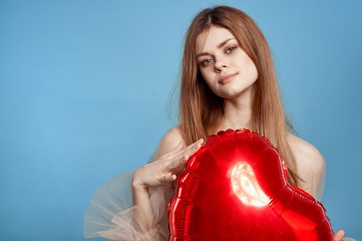 cheerful woman red heart in the hands of the balloon blue background. High quality photo