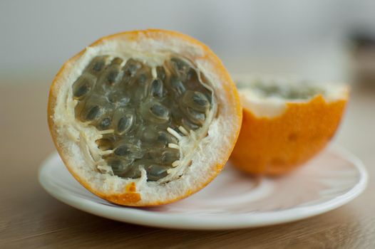 Fresh organic ripe granadilla or yellow passion fruit cut in half on a wooden board. Exotic fruits, healthy eating concept.