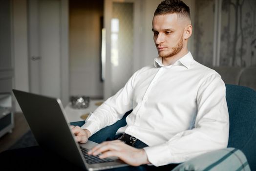 a young man works at a laptop on the couch at home. High quality photo