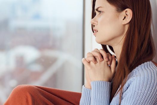 woman with sad expression sits by the window with a plaid. High quality photo