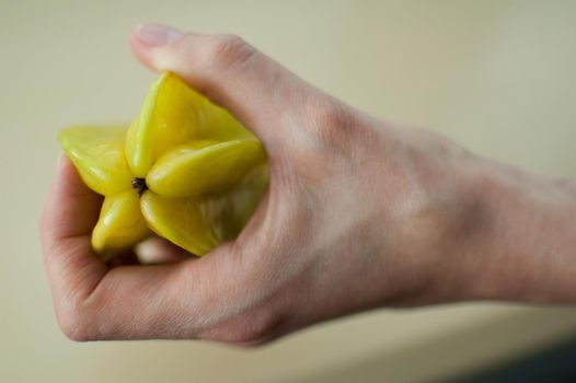 Female hands are holding exotic ripe starfruit or averrhoa carambola. Healthy food, fresh organic star apple fruit