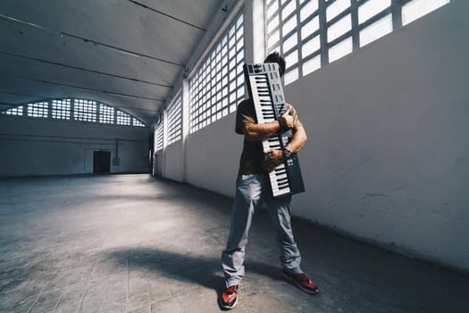 Musician Concept  artist keeping his keyboard and showing his love for the music in a factory interior   