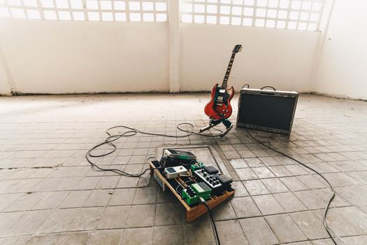 Electric guitar with amplifier and Electric guitar stomp box effectors and cables on studio floor.
