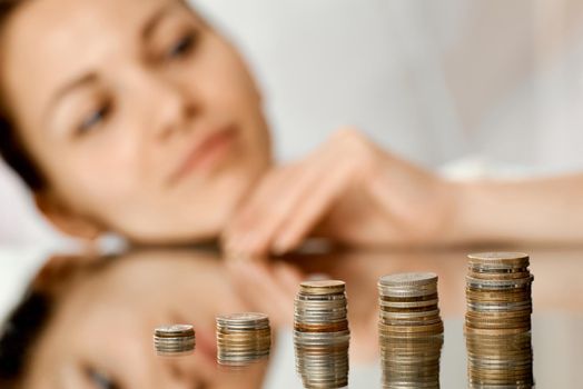 Girl dreams of looking at her hoardings in the form of stacks of coins like a ladder. High quality photo