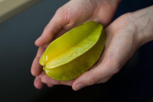 Female hands are holding exotic ripe starfruit or averrhoa carambola. Healthy food, fresh organic star apple fruit