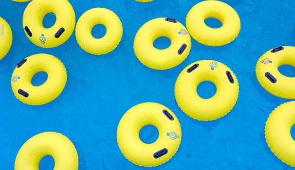 Several yellow swimming inflatable rescue laps on the blue water in the pool . High quality photo