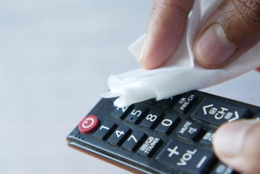 Cleaning Tv remote control with an antibacterial fabric tissue.