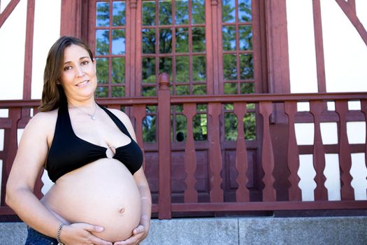 Seven months pregnant young woman dressed in black bikini and jeans