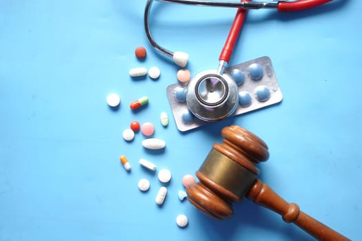 Top view of gavel, stethoscope and pills on white background.