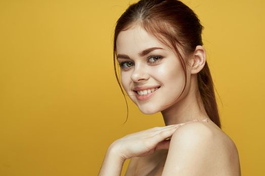 pretty woman naked shoulders and posing clear skin yellow background. High quality photo