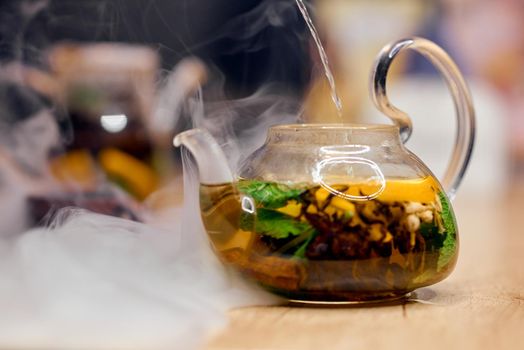 Transparent kettle filled with hot water stands in smoke . High quality photo